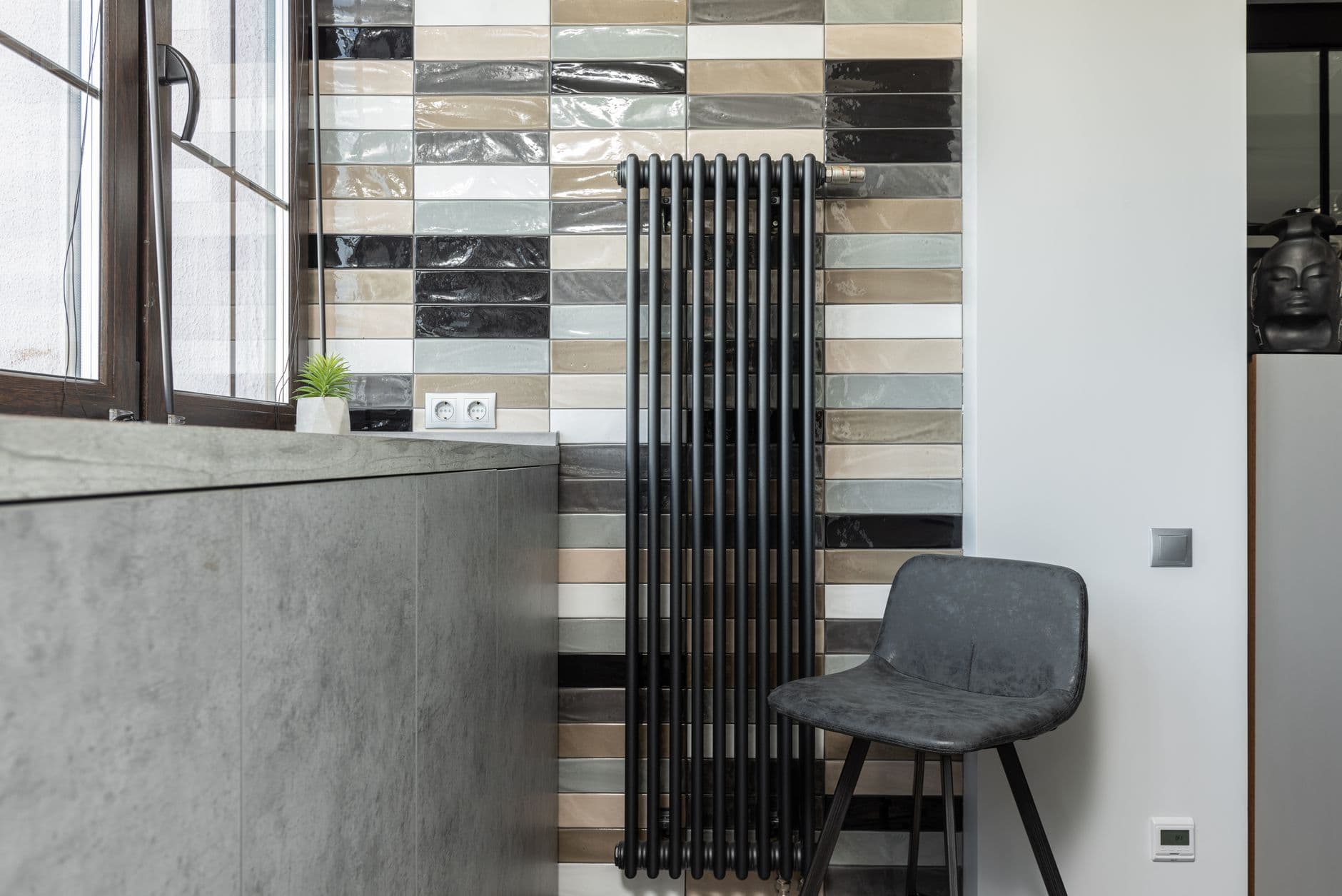 A wall-mounted heater standing beside an armchair in a tiled room