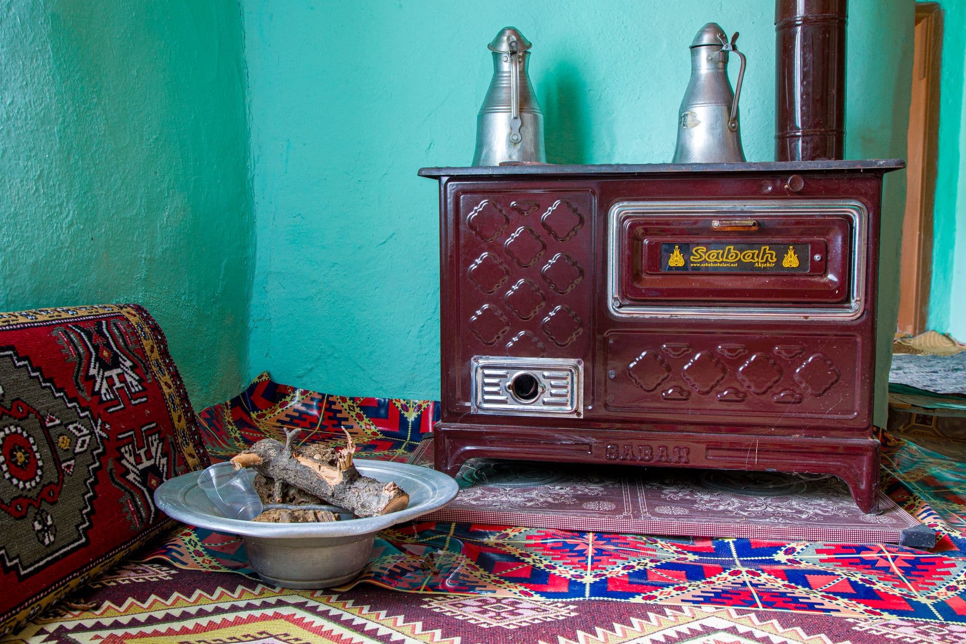 A rustic stove with wood in a cozy, brightly furnished room