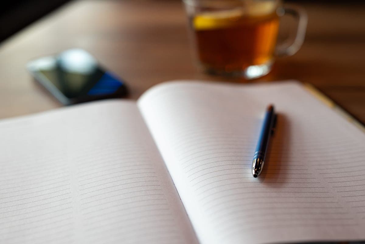 A notebook and pen beside a shopping list