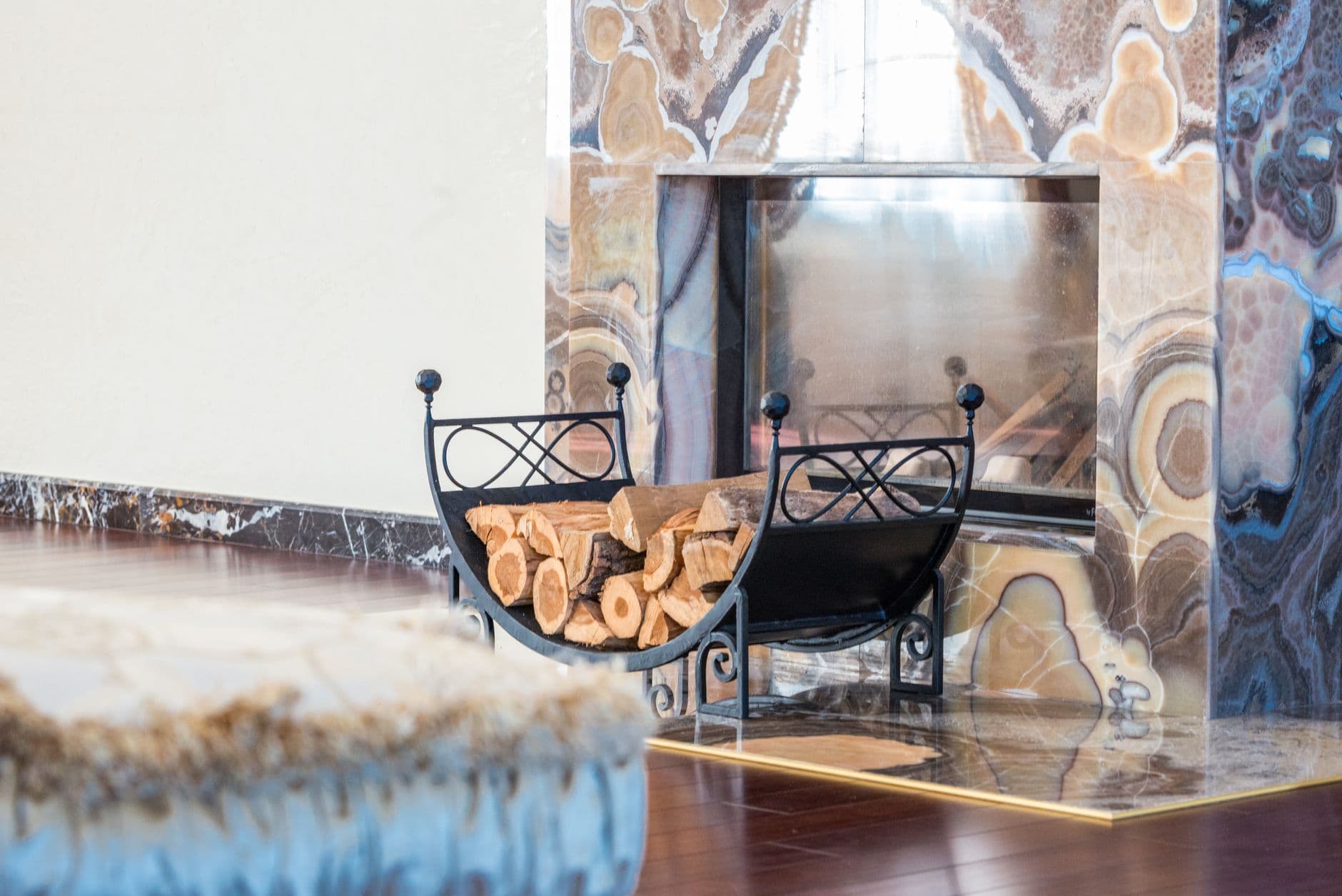 A modern lounge with a patterned marble fireplace surround and a black metal log rack beside it