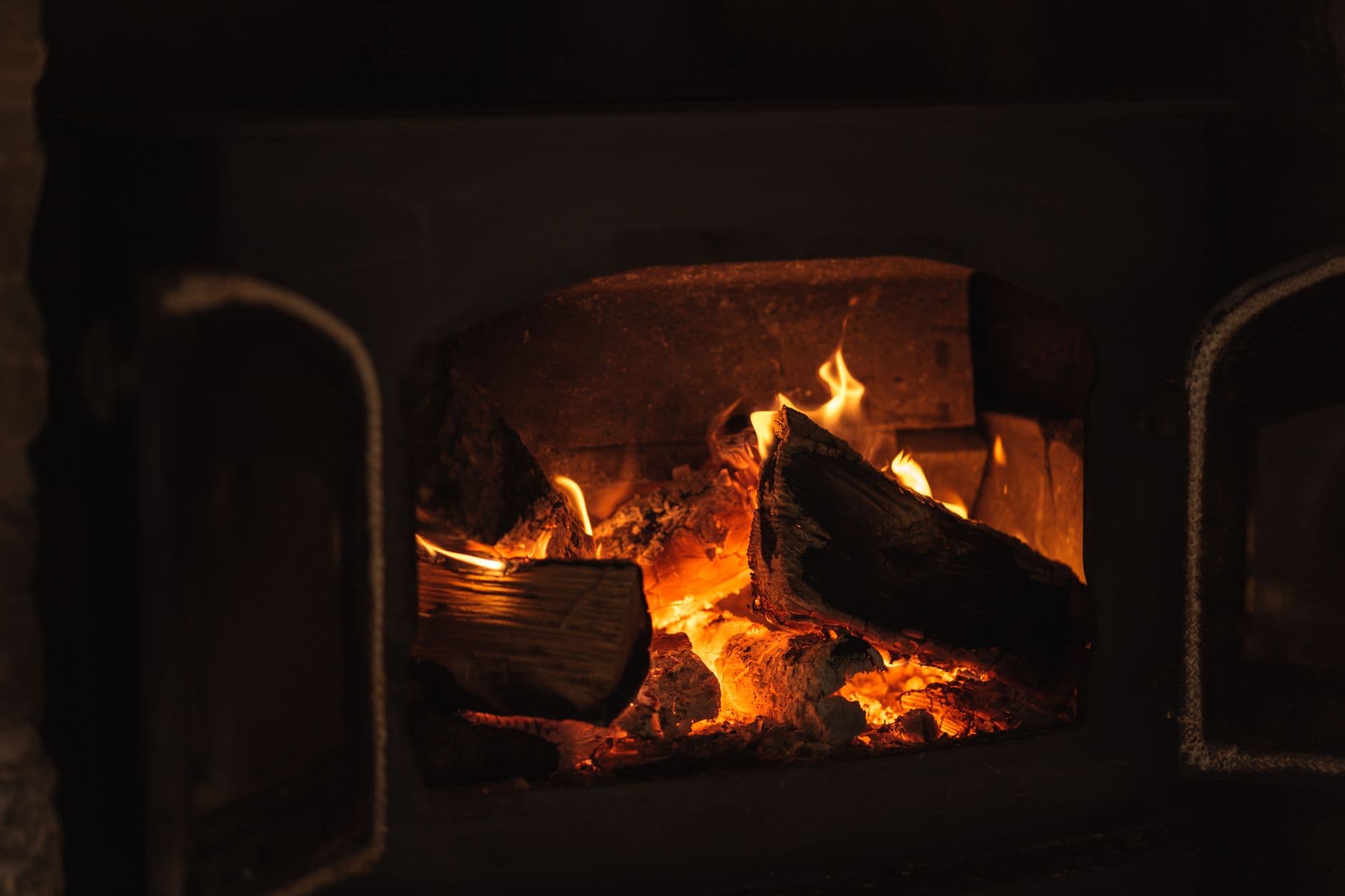 A fire burning with bright orange flames in a fireplace in an otherwise dark room
