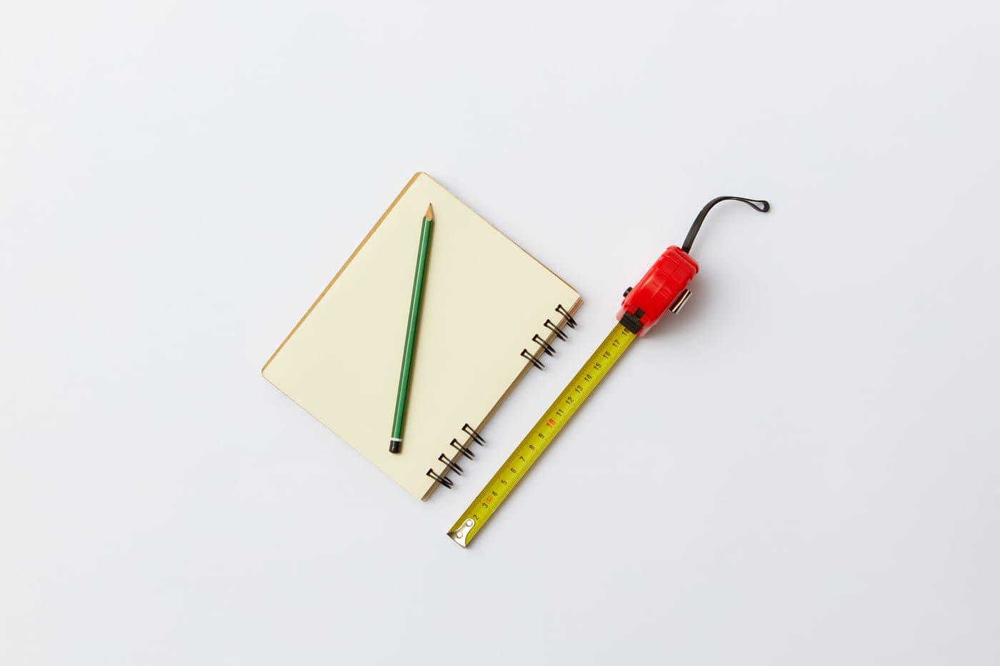 A notebook with measurements written on it beside a pencil