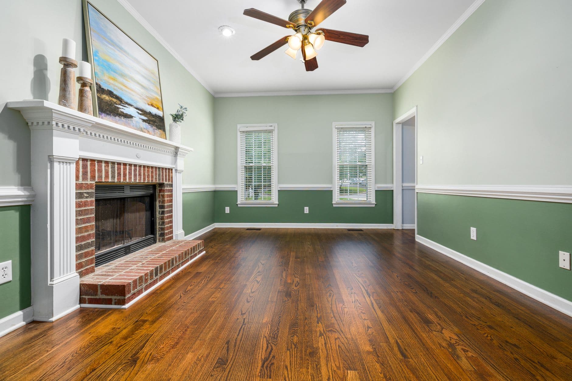 An empty living room with a brick fireplace and wooden floors