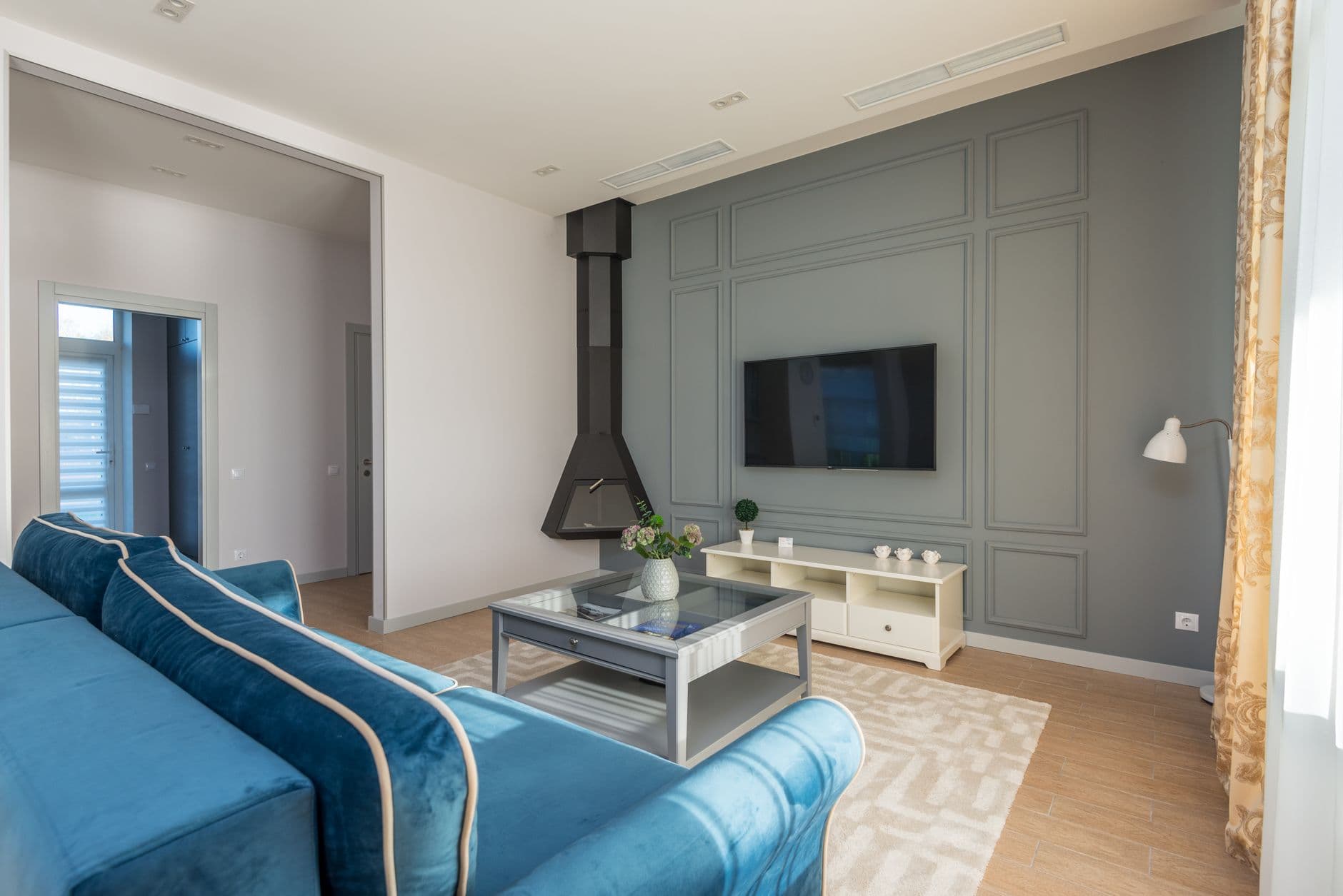 A stylish living room with a wall-mounted television and feature wall
