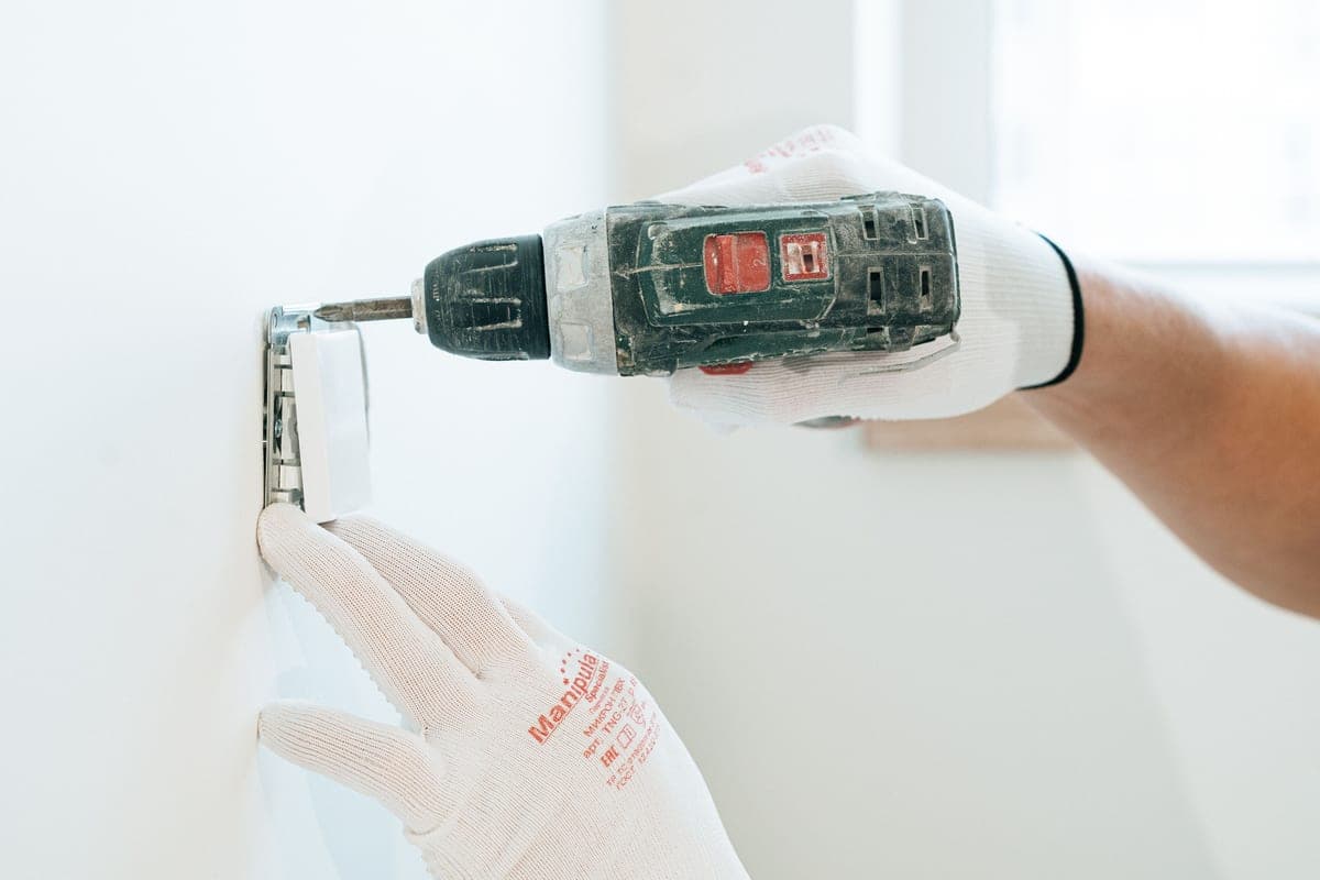An electrician working at a wall outlet