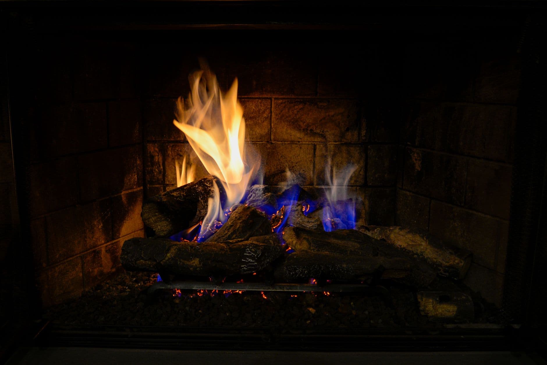 A fire burning in an indoor fireplace on a winter evening