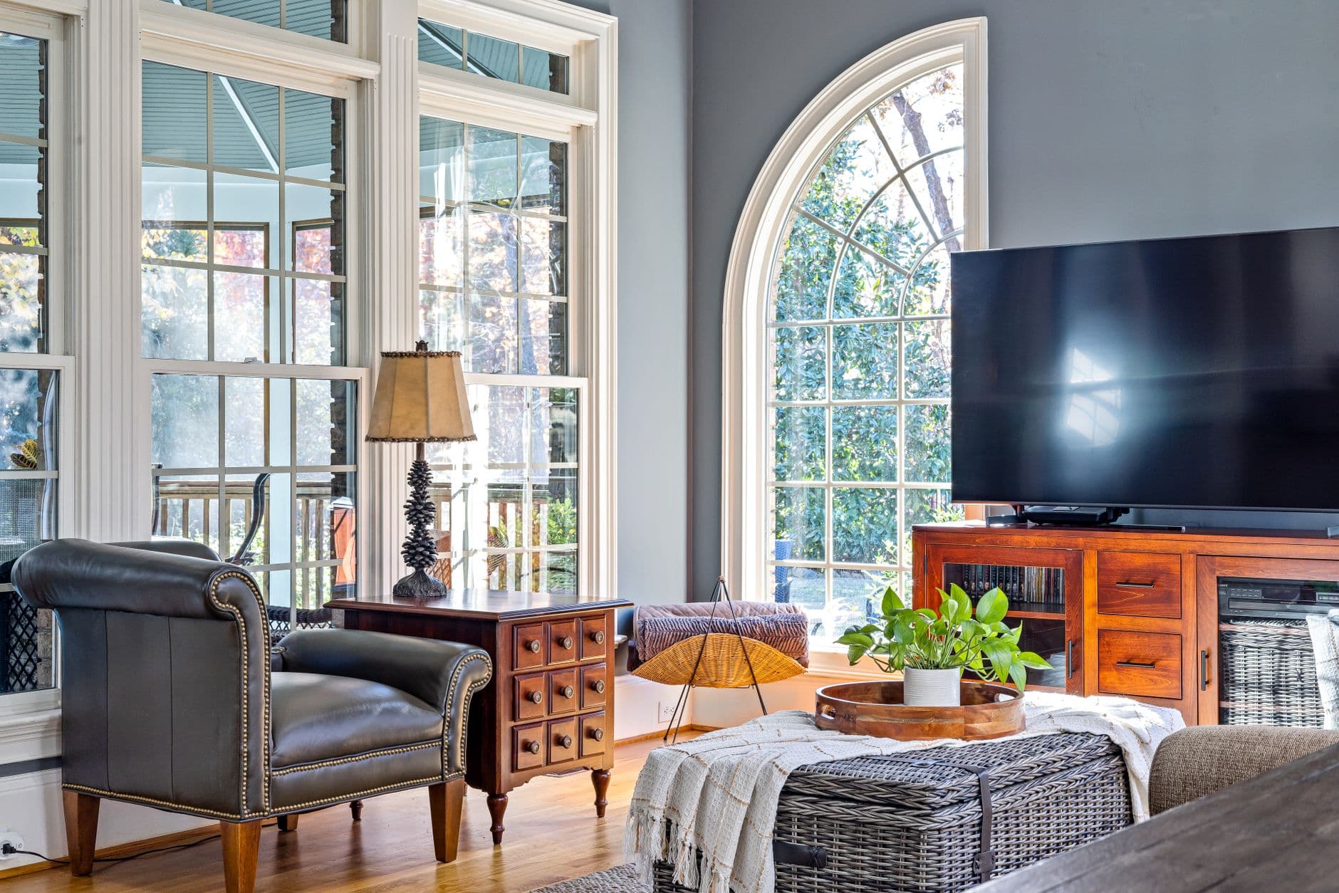 A wooden media console with cabinet doors and drawers below a television in a bright living room