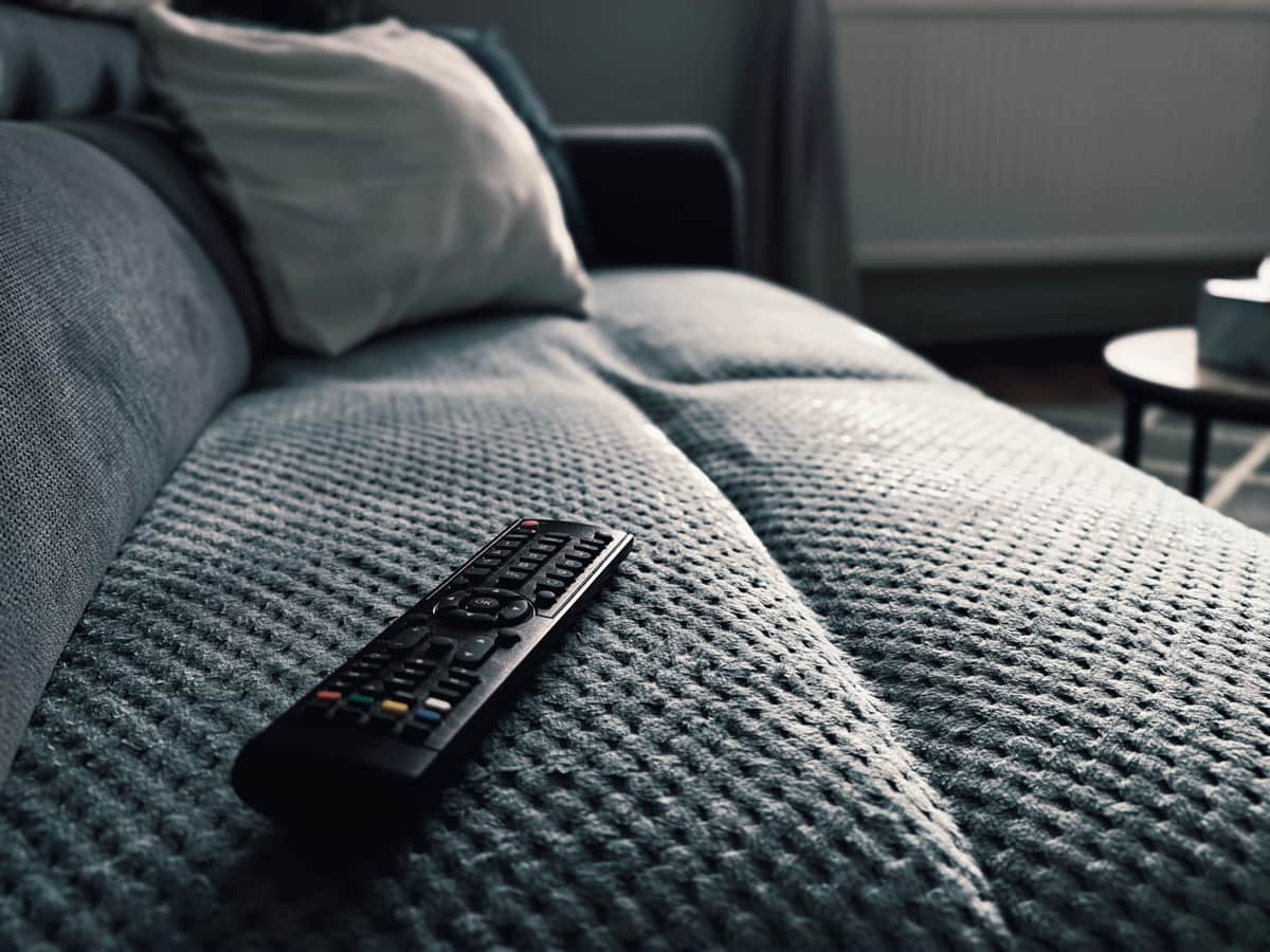 A television remote resting on a sofa arm