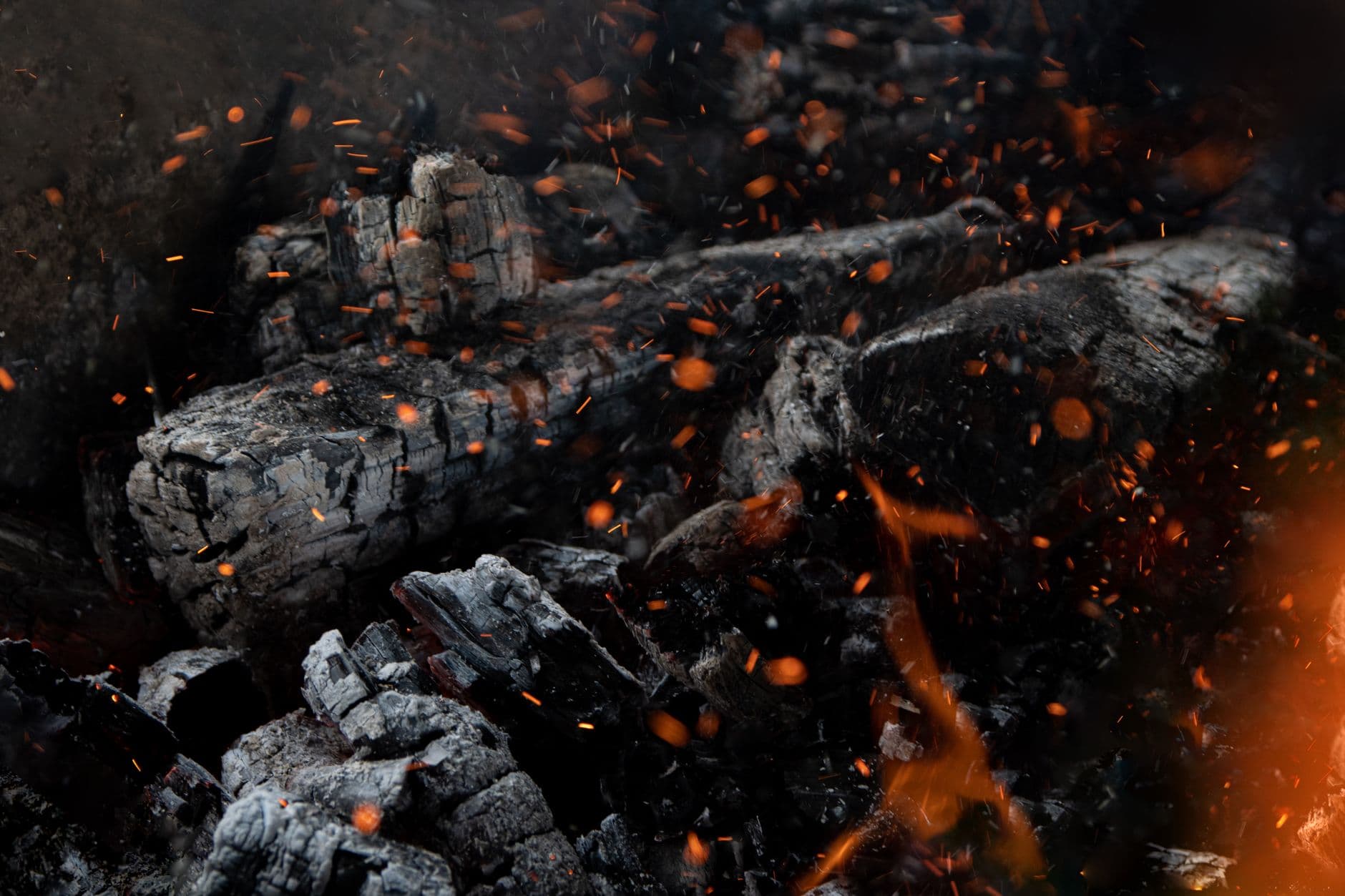 A close-up of glowing embers and burnt charcoal with sparks