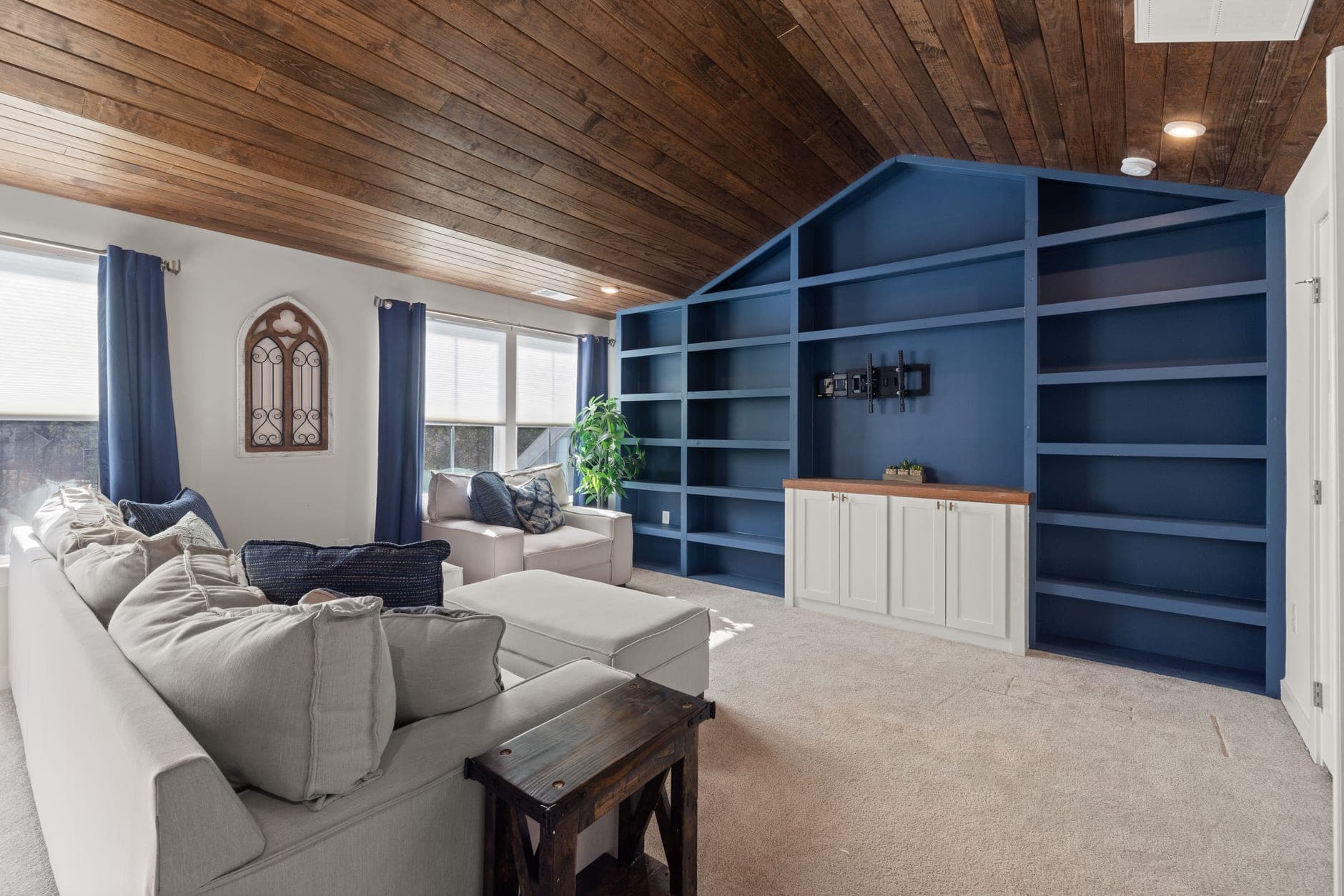 A living room wall of built-in painted shelving and cabinetry with a television mount